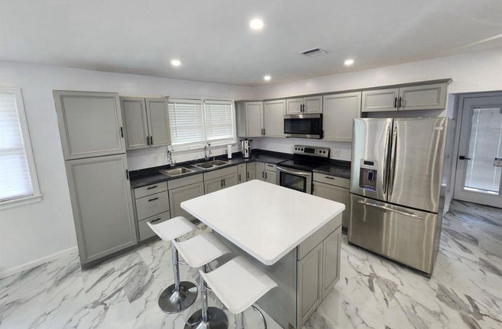 Contemporary chef’s staging kitchen with central island and breakfast bar